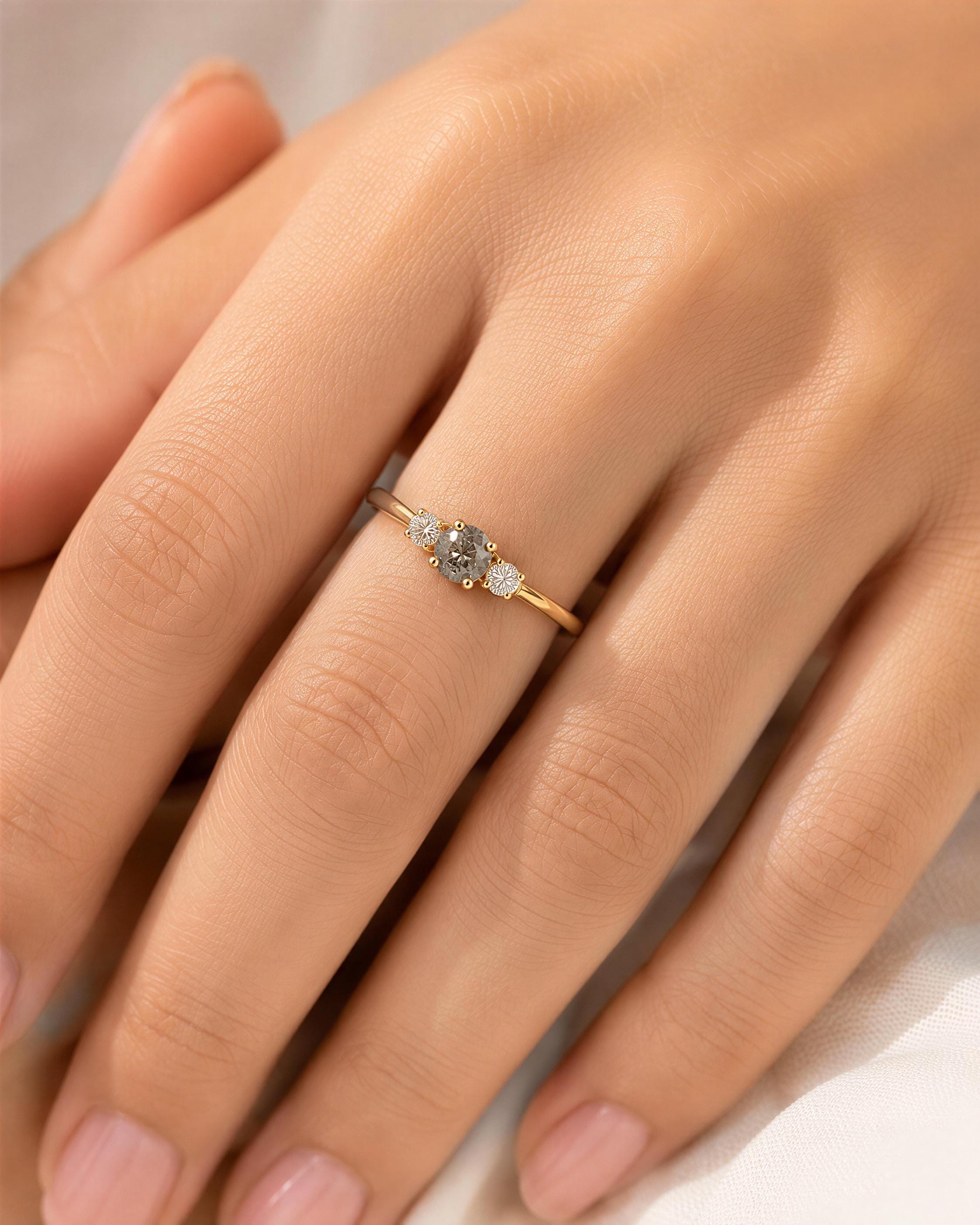 A close-up of a person's hand wearing a gold ring with a diamond and three smaller diamonds.