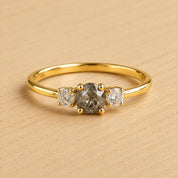 A gold ring with a large central diamond and two smaller diamonds on either side.