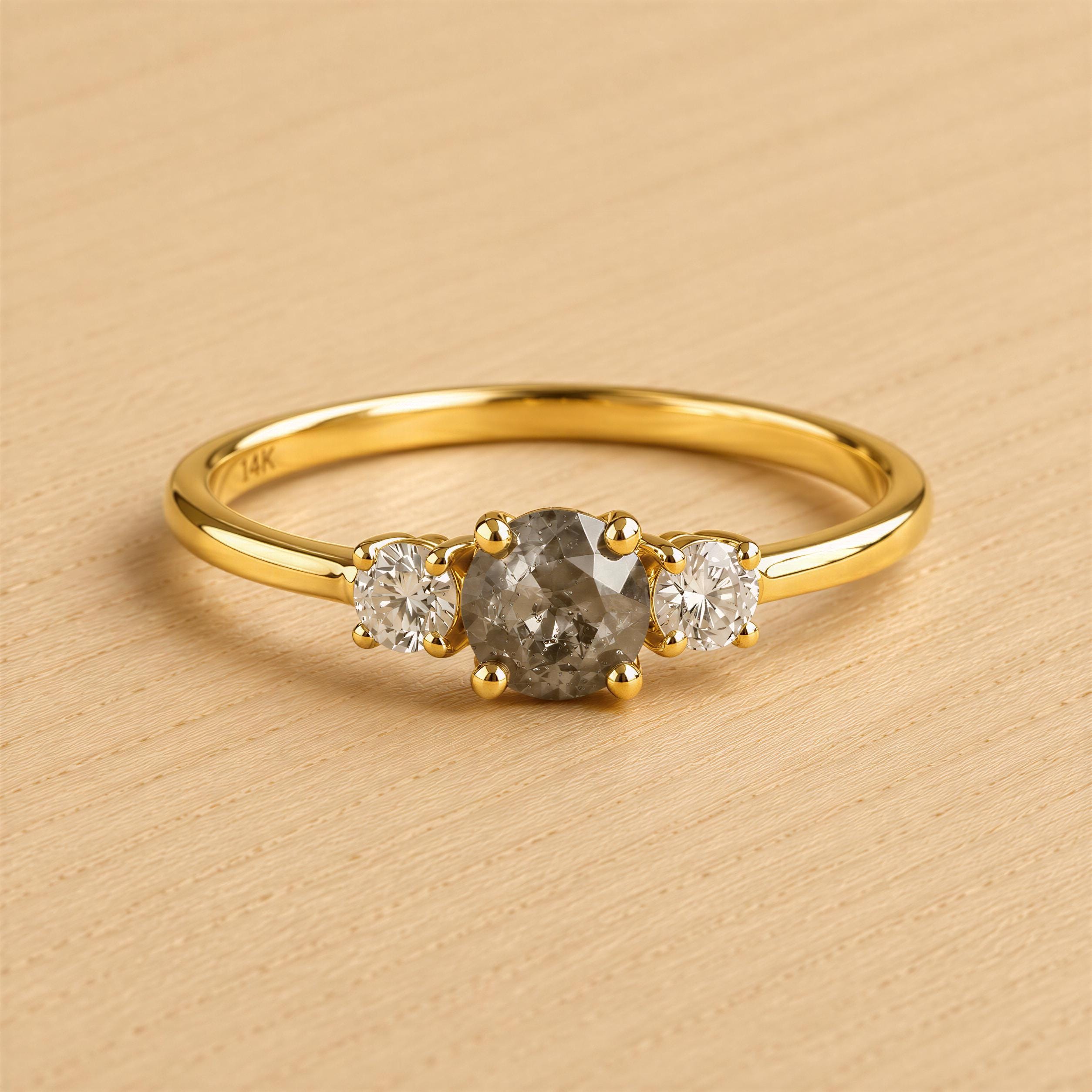 A gold ring with a large central diamond and two smaller diamonds on either side.