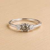 A silver ring with a large central diamond surrounded by two smaller diamonds on either side.