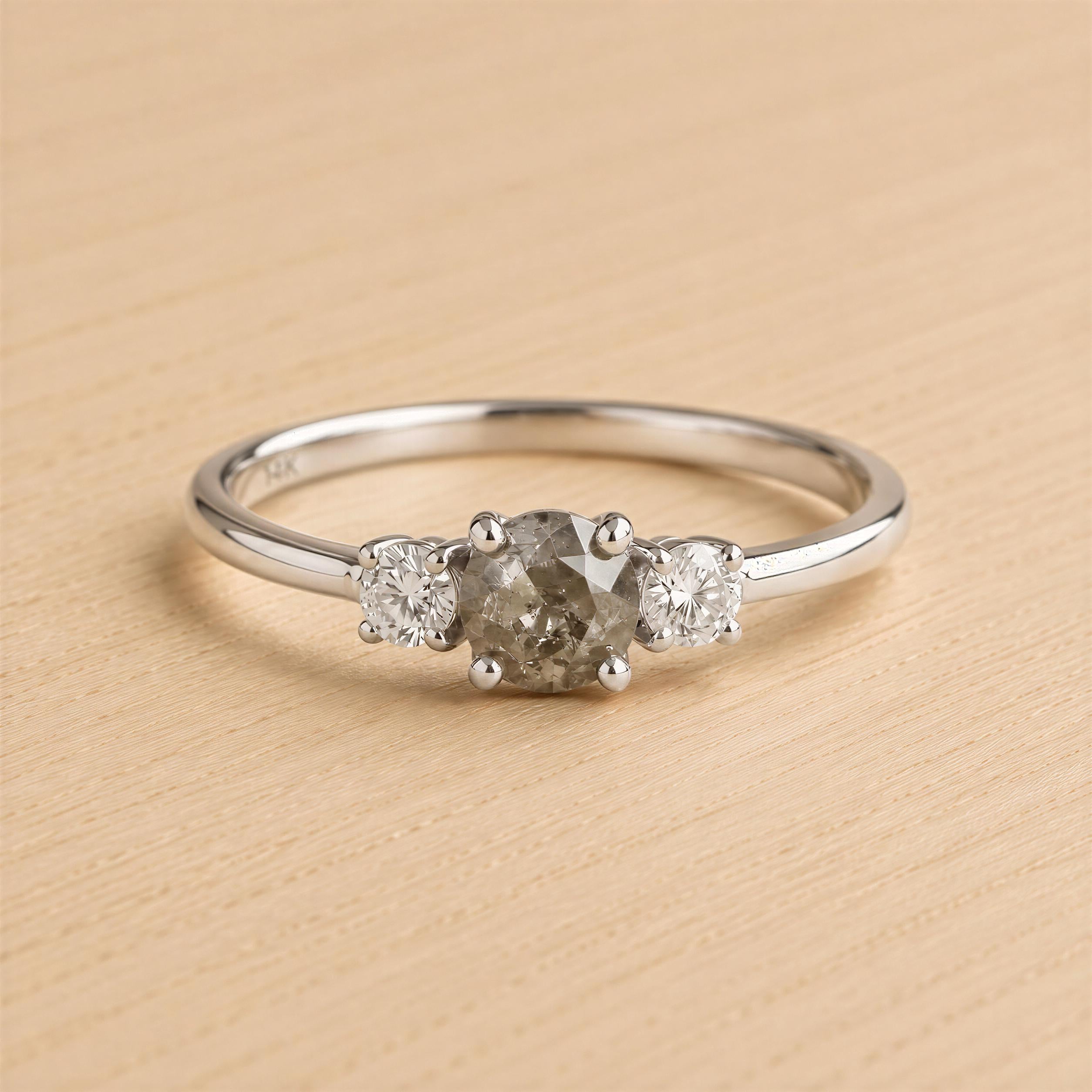 A silver ring with a large central diamond surrounded by two smaller diamonds on either side.