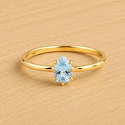 A gold ring with a blue aquamarine gemstone set in the center.