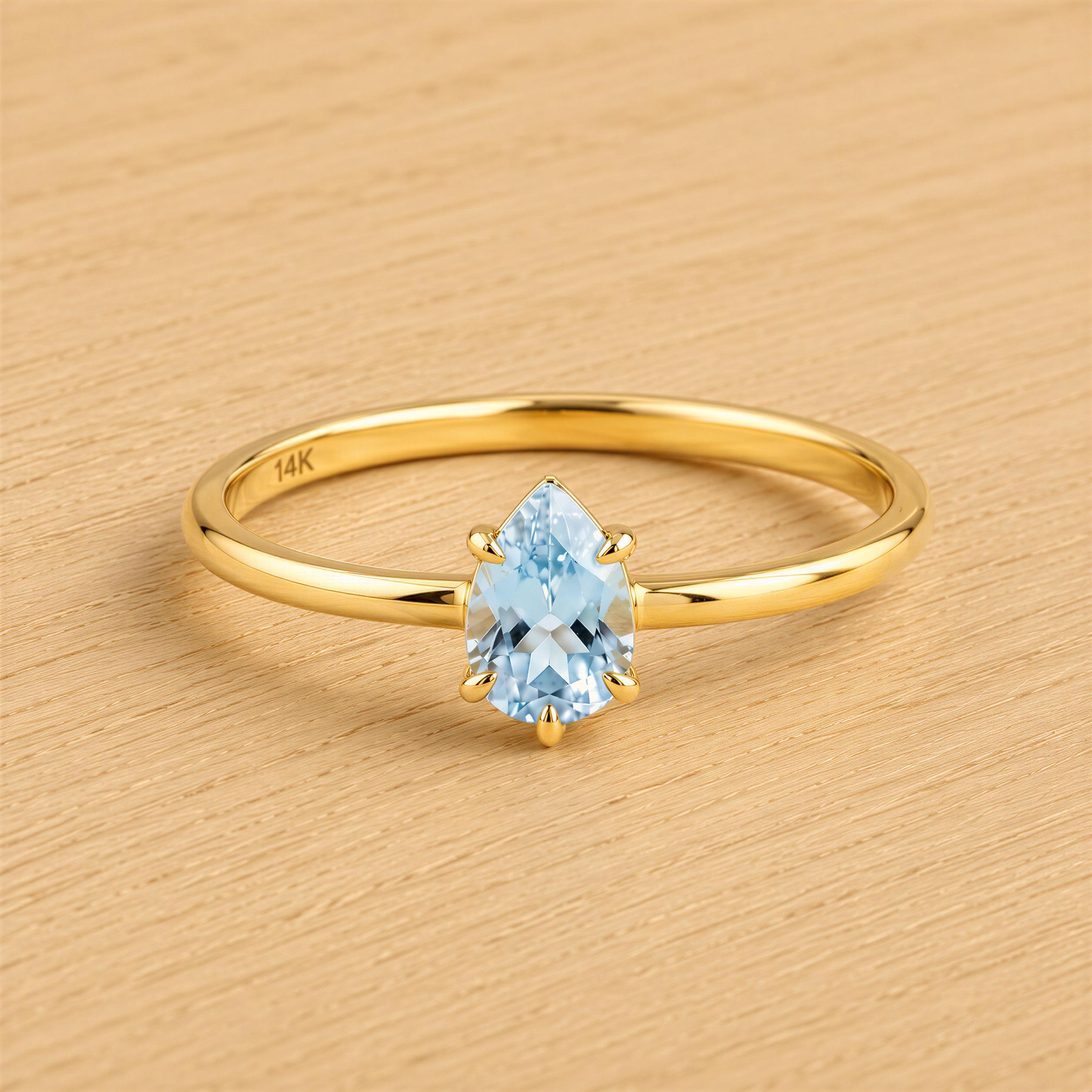 A gold ring with a blue aquamarine gemstone set in the center.