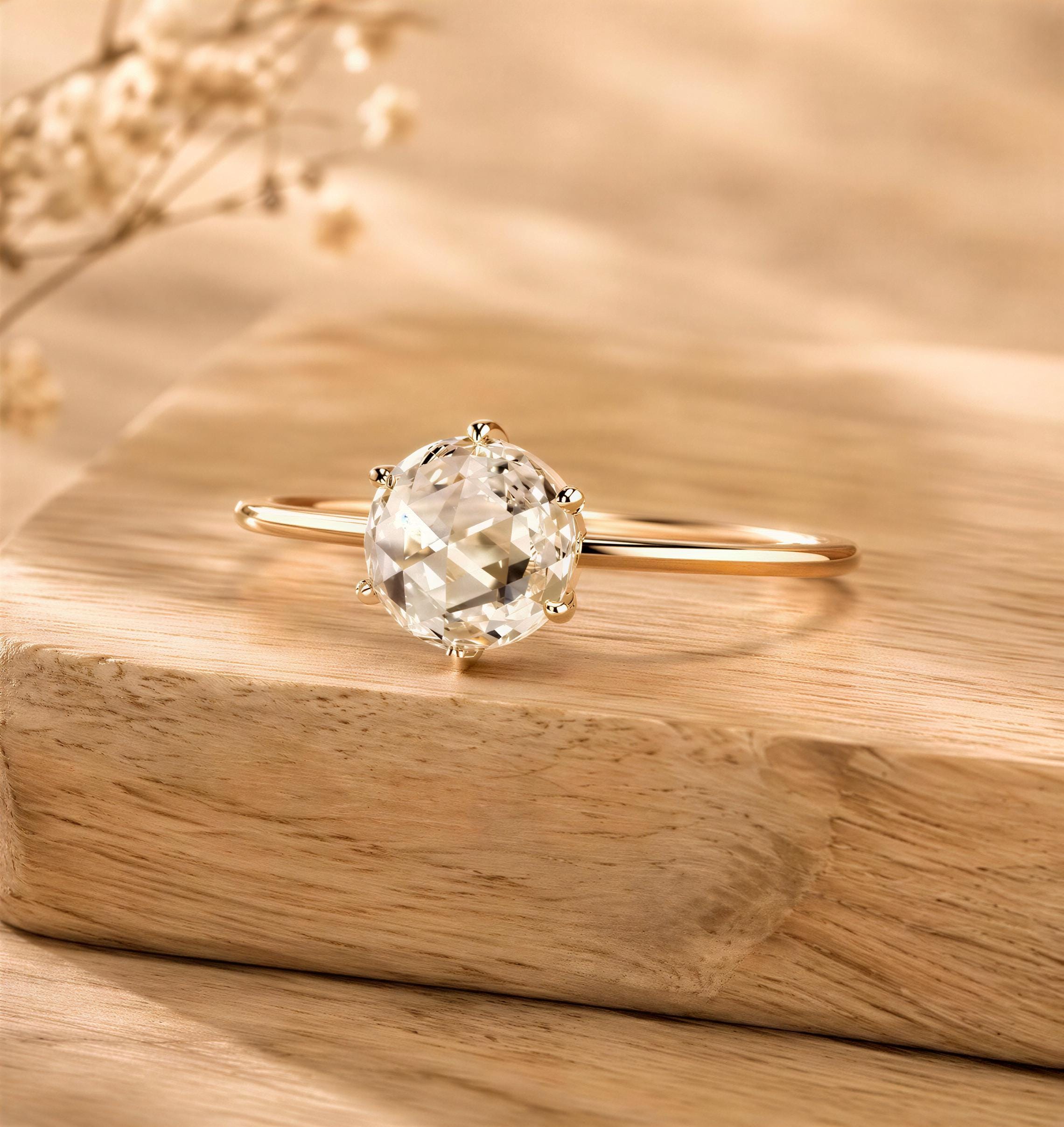 A diamond engagement ring with a large oval-shaped diamond set in a gold band, resting on a wooden surface.