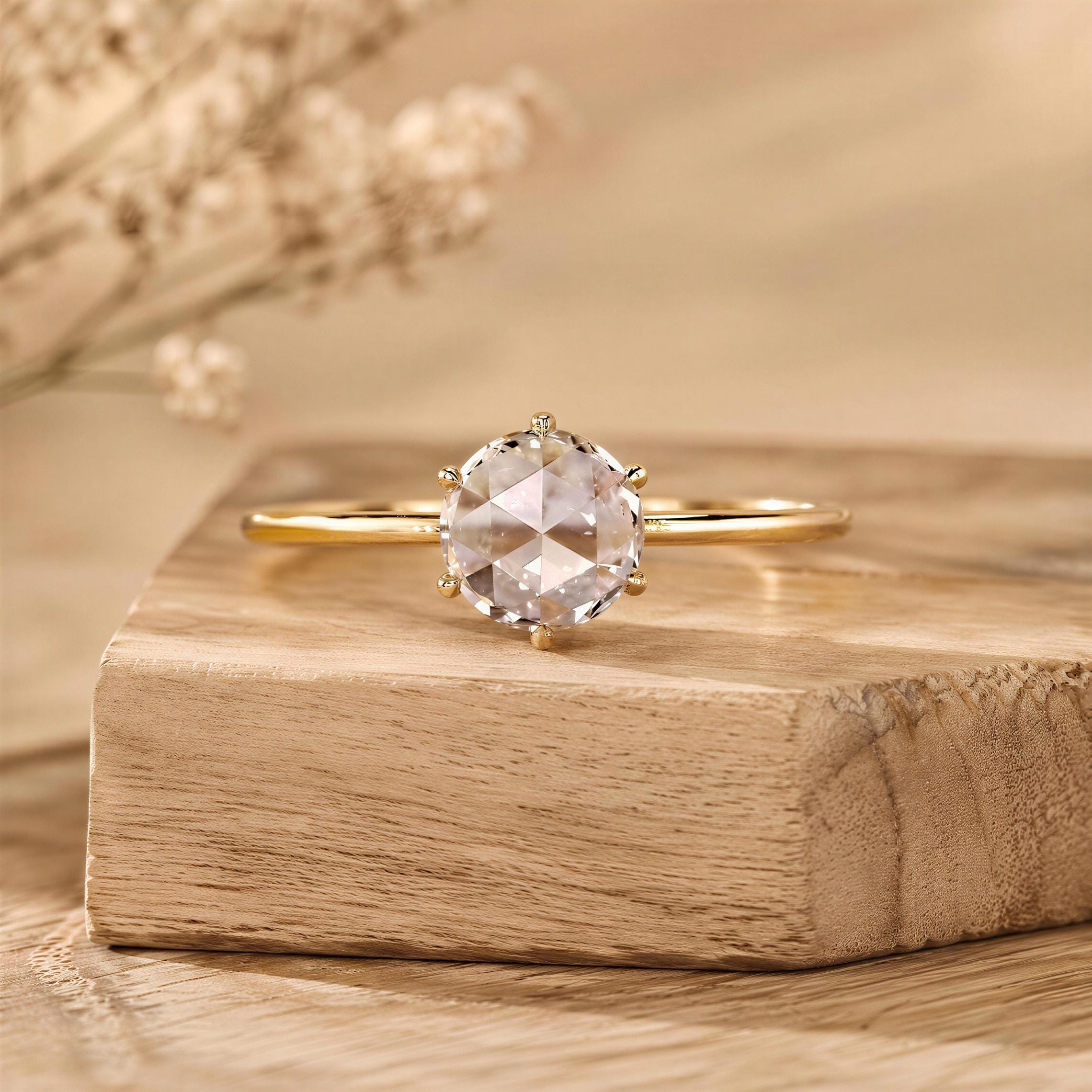 A diamond engagement ring with a large, clear gemstone is displayed on a wooden surface, with a blurred background.