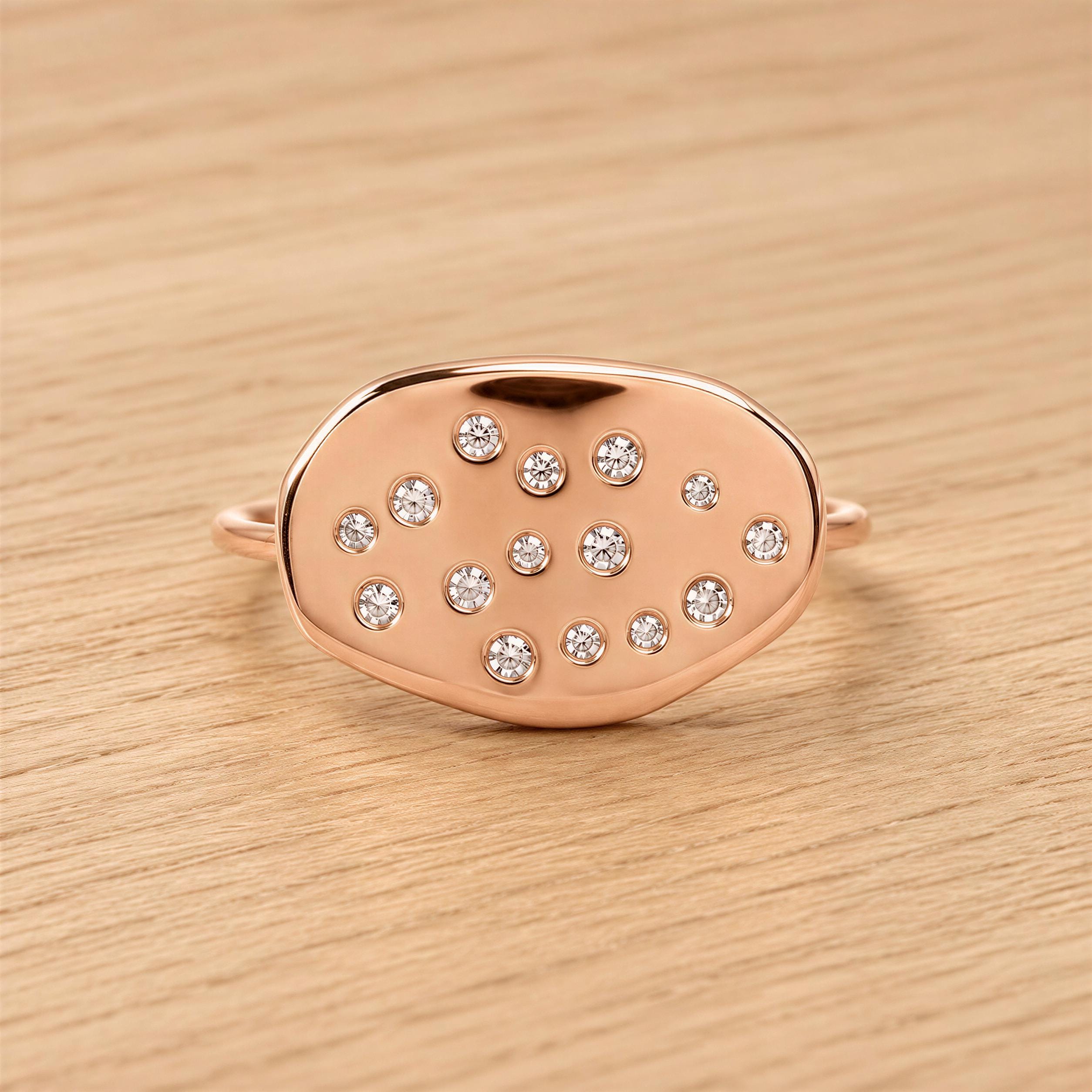 A rose gold ring with a large oval-shaped stone in the center, surrounded by smaller diamonds.
