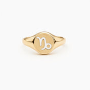 A gold ring with a round embossed seal featuring the astrological sign of Capricorn.