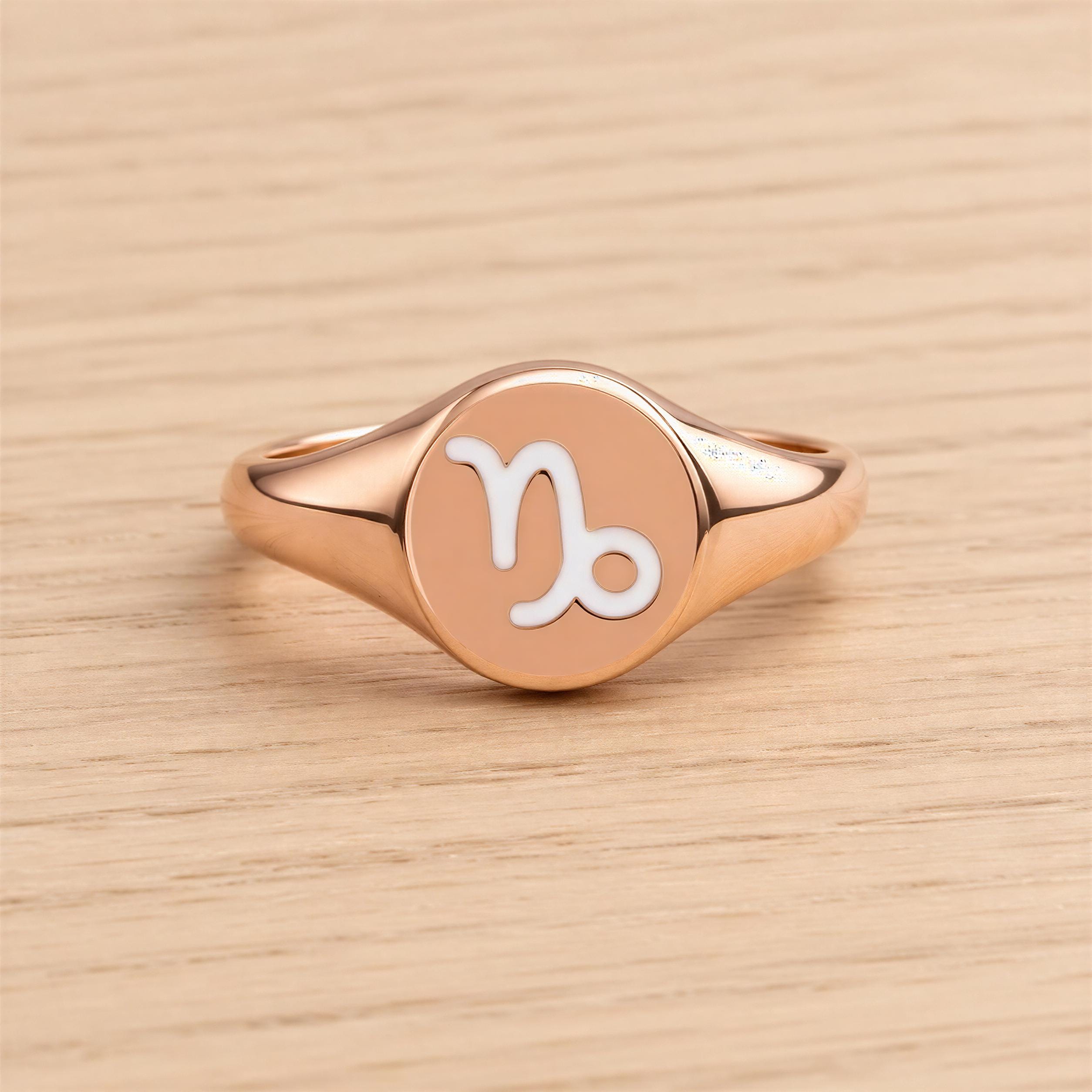 A rose gold ring with a round, engraved signet style ring featuring the astrological sign of Capricorn.