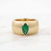 A gold ring with a large oval-shaped green gemstone set in the center.