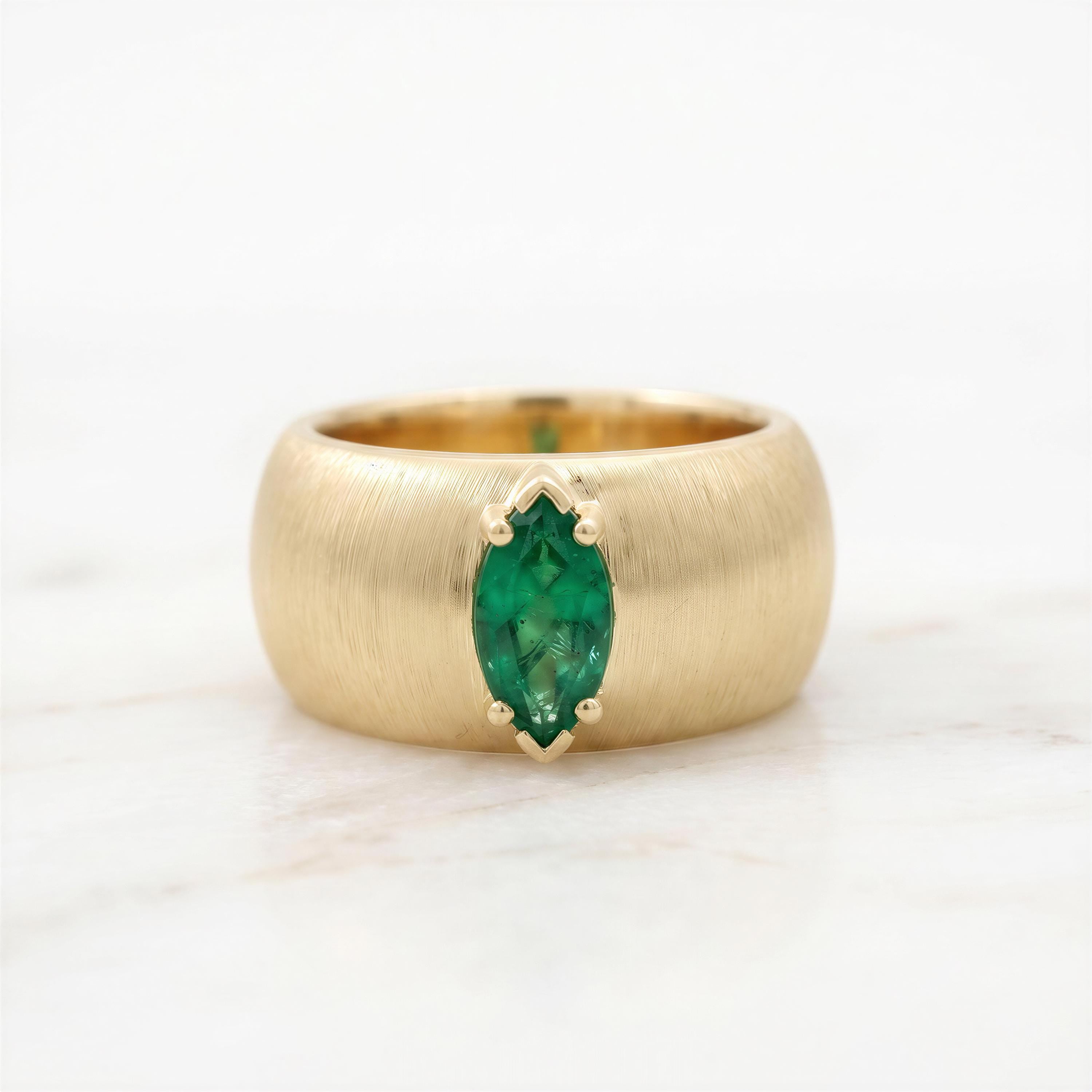 A gold ring with a large oval-shaped green gemstone set in the center.