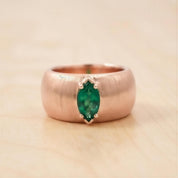A close-up image of a gold ring with a large green gemstone set in the center.