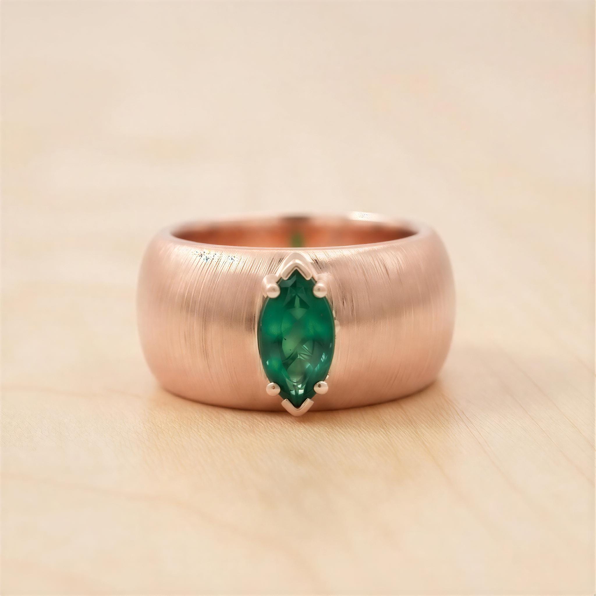A close-up image of a gold ring with a large green gemstone set in the center.