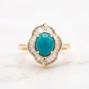 A gold ring with a large turquoise gemstone at the center, surrounded by smaller diamonds.