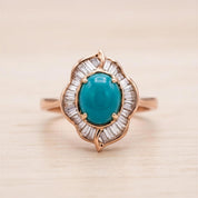A gold ring with a large turquoise gemstone at the center, surrounded by smaller diamonds.