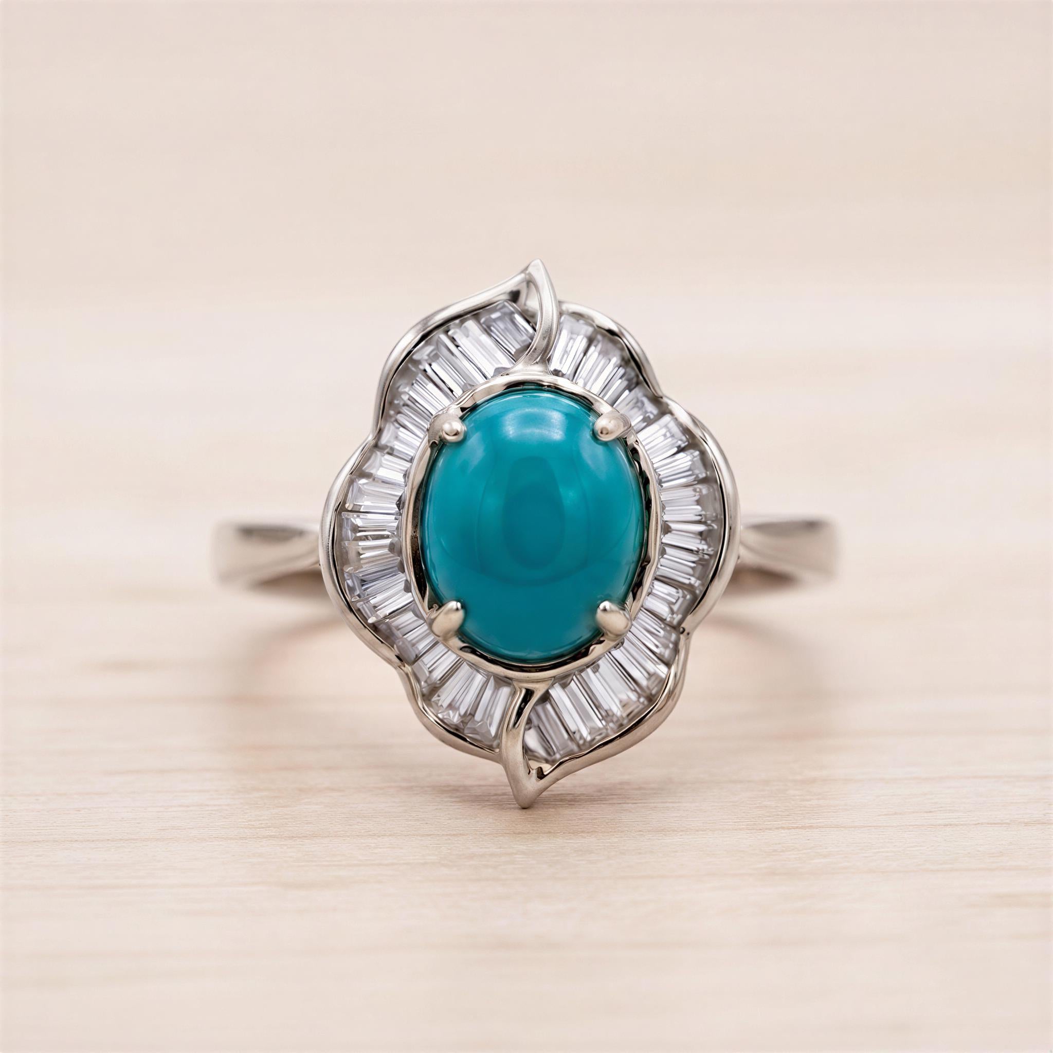 A silver ring with a large turquoise gemstone at the center, surrounded by smaller diamonds.