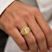 A close-up of a person's hand wearing a gold ring with a lion's head design.
