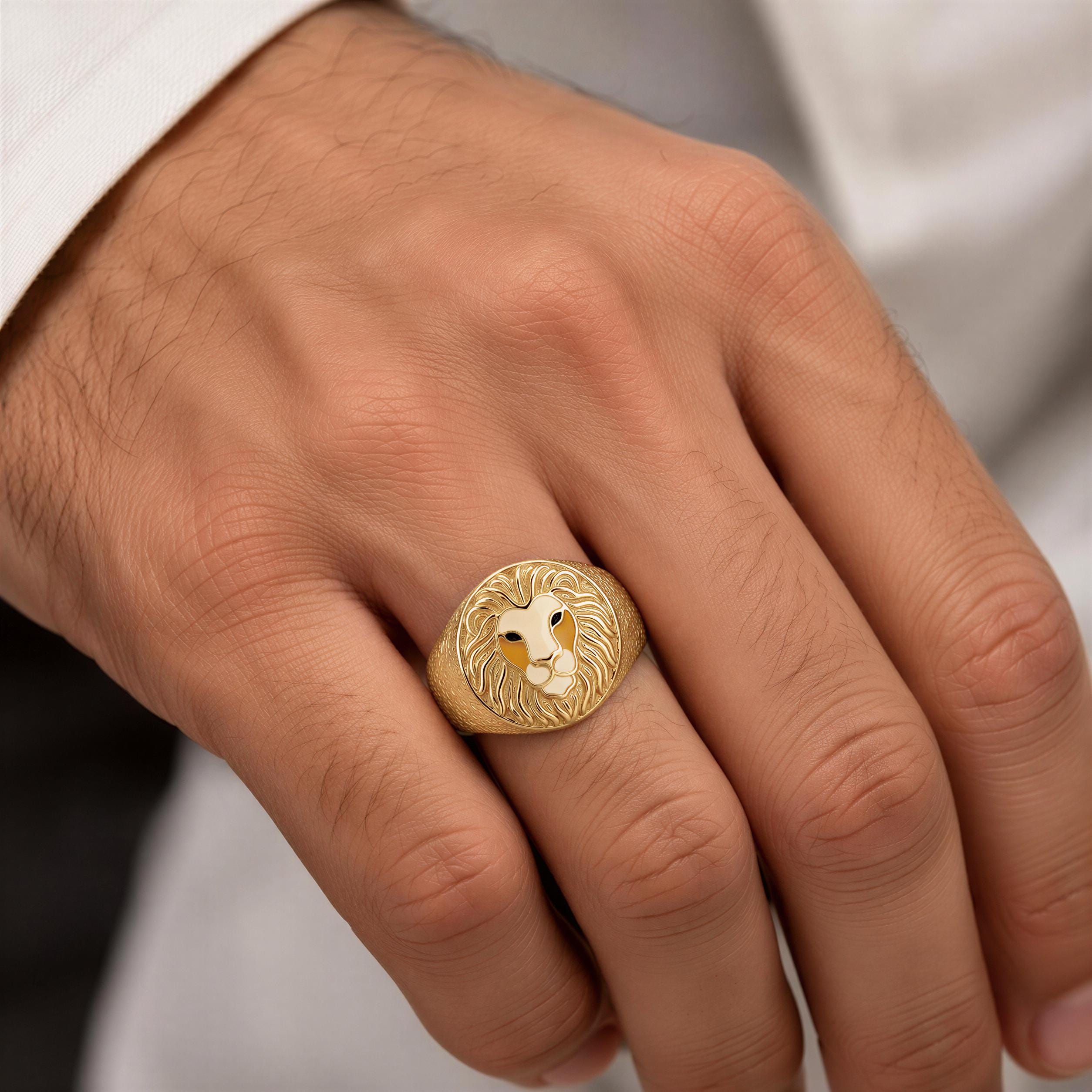 A close-up of a person's hand wearing a gold ring with a lion's head design.