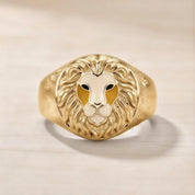A gold ring with a detailed lion's head design on the front.