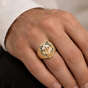 A close-up image of a person's hand wearing a gold ring with a fox design.