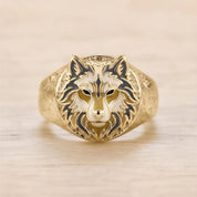 A gold ring with a detailed design of a wolf's head on the front.