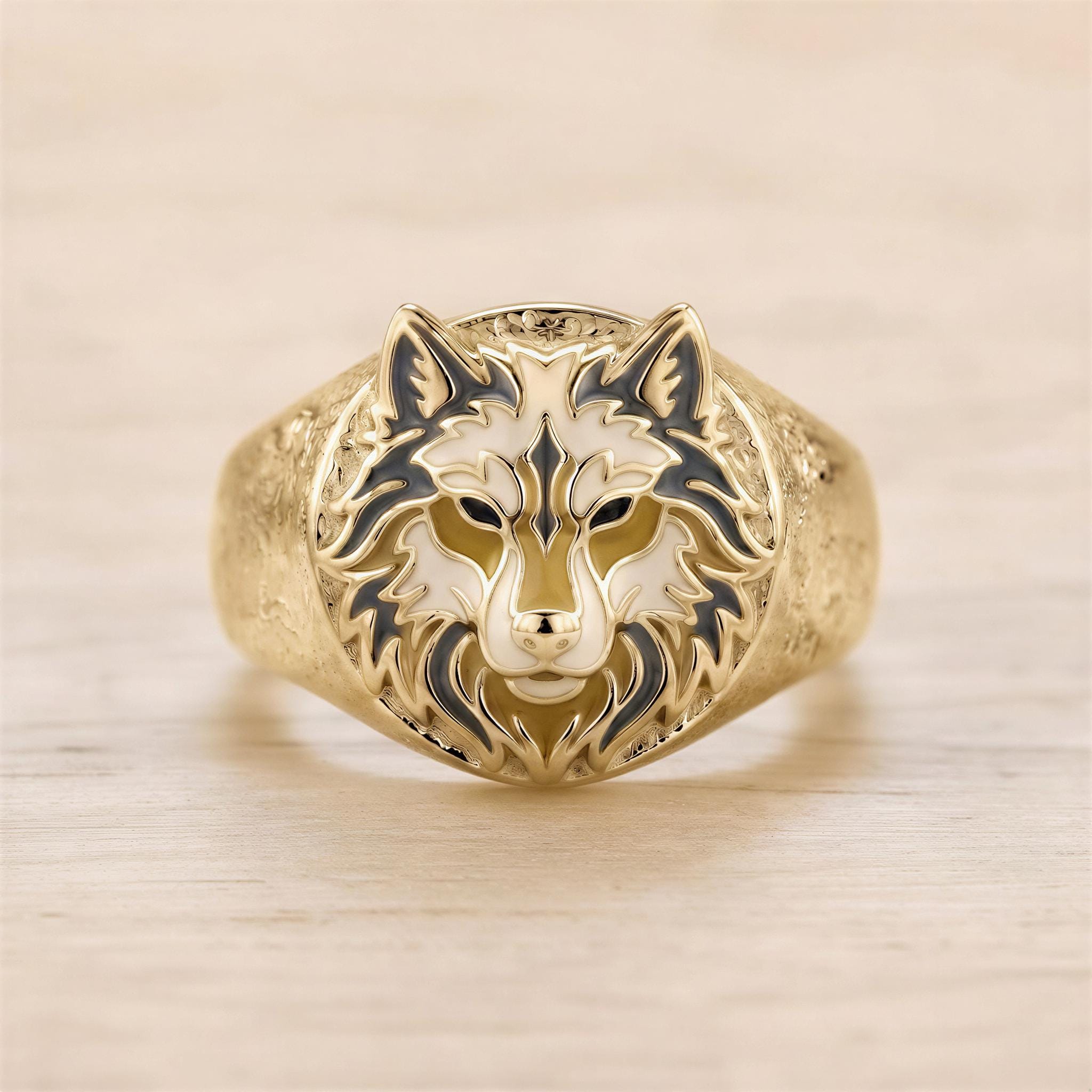 A gold ring with a detailed design of a wolf's head on the front.