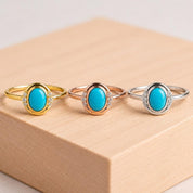 May include: Three rings featuring oval-shaped turquoise cabochons set in metal bands. The left ring is yellow gold, the center is rose gold, and the right is silver. Each ring has small clear stones flanking the central turquoise gemstone.
