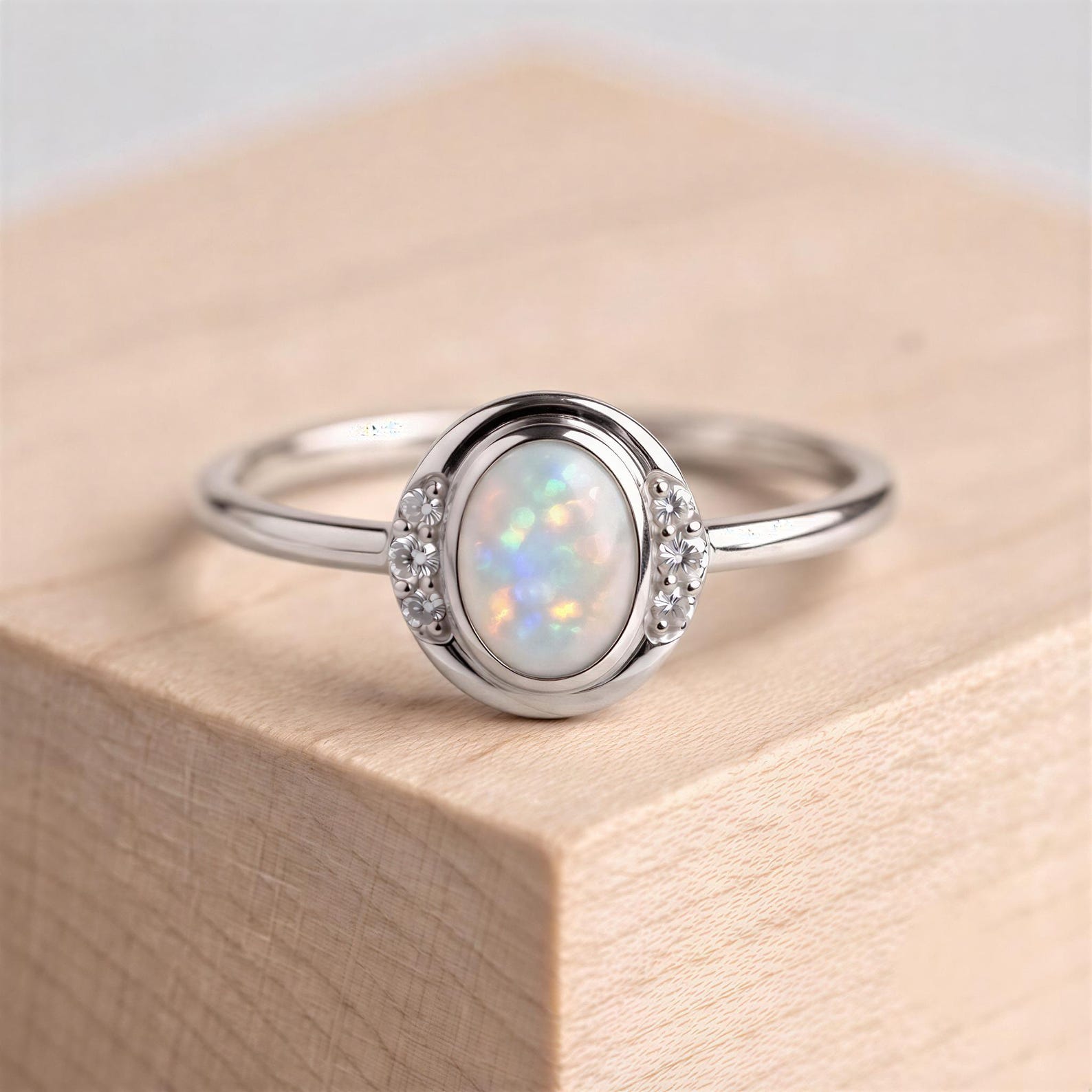 A silver ring with a large oval-shaped opal stone set in the center, surrounded by smaller diamonds.