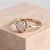 A gold ring with a large oval-shaped opal gemstone set in the center, surrounded by smaller diamonds.