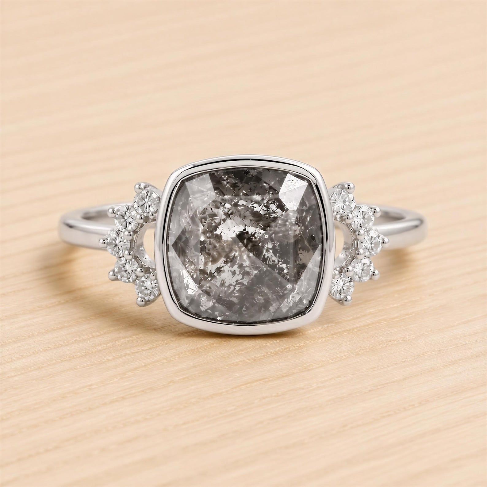 A silver ring with a large, irregularly shaped gray gemstone in the center, surrounded by smaller diamonds on either side.