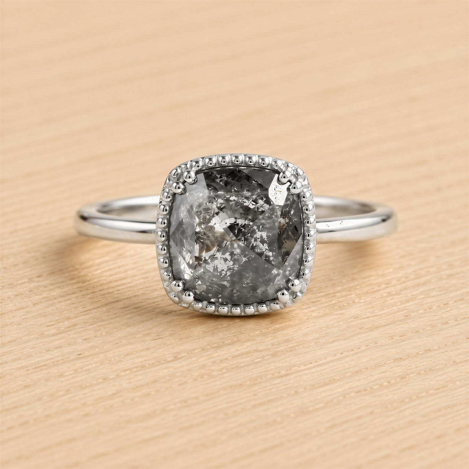 A silver ring with a large, irregularly shaped diamond as the centerpiece, set in a halo of smaller diamonds.