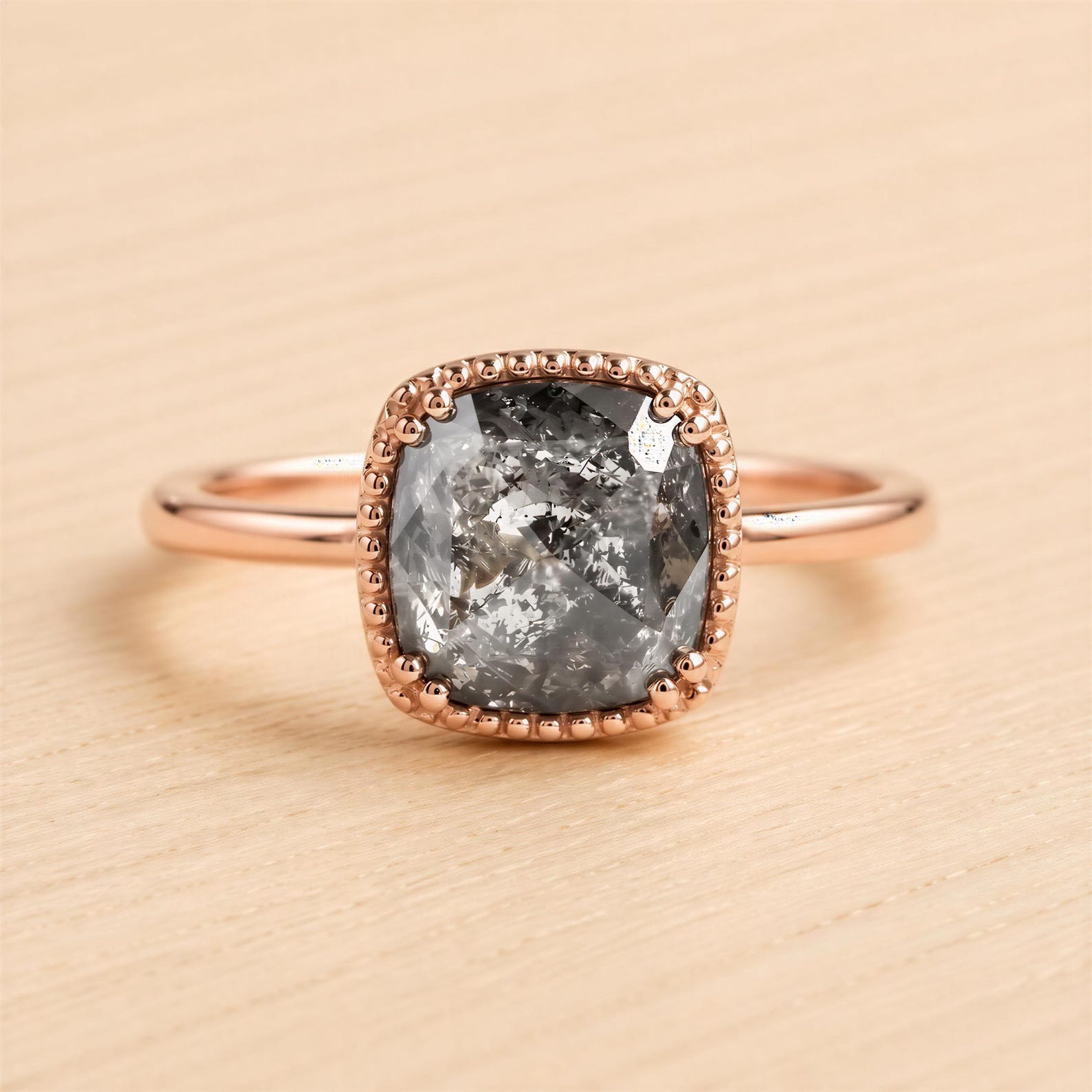 A rose gold ring with a large, irregularly shaped gray diamond as the centerpiece.