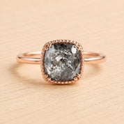 A rose gold ring with a large, irregularly shaped gray diamond as the centerpiece.