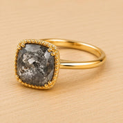 A gold ring with a large, irregularly shaped diamond as the centerpiece, set in a gold band.