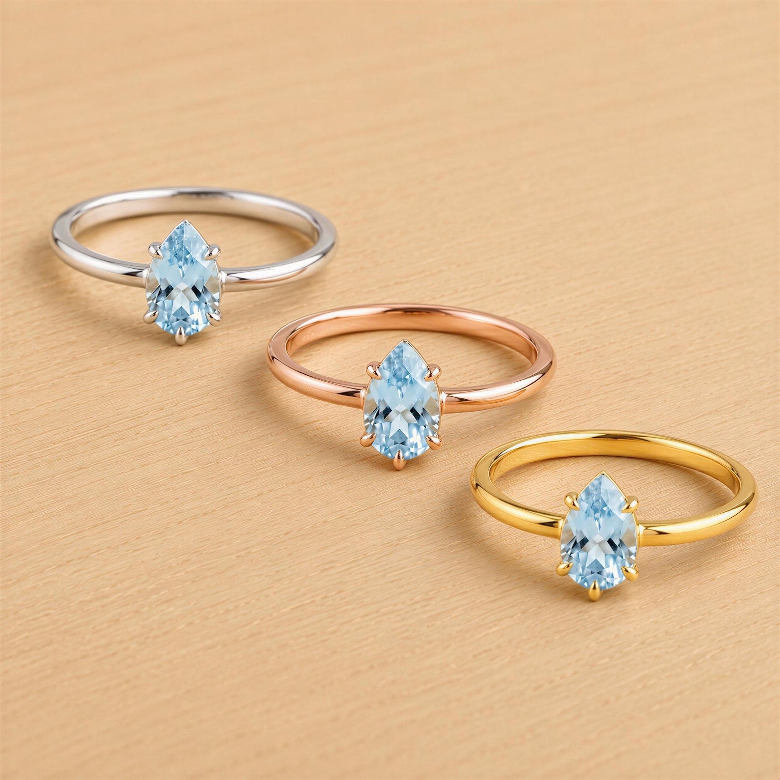 Three rings with blue gemstones are displayed on a wooden surface.