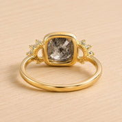 A gold ring with a large diamond in the center, surrounded by smaller diamonds on either side.