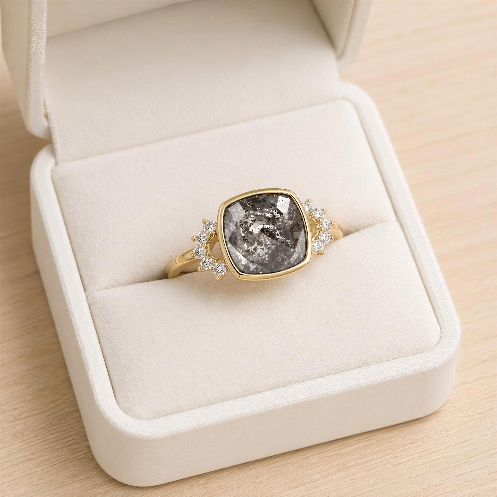 A gold ring with a large gray gemstone, placed in a white jewelry box.
