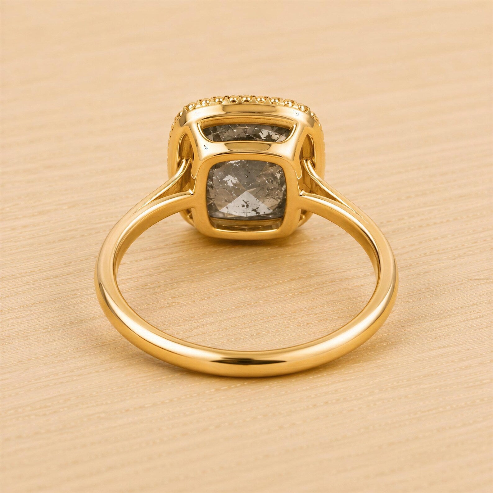 A gold ring with a large diamond set in the center, resting on a wooden surface.