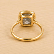 A gold ring with a large diamond set in the center, resting on a wooden surface.