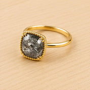 A gold ring with a large, square-shaped diamond as the centerpiece, set in a gold band.