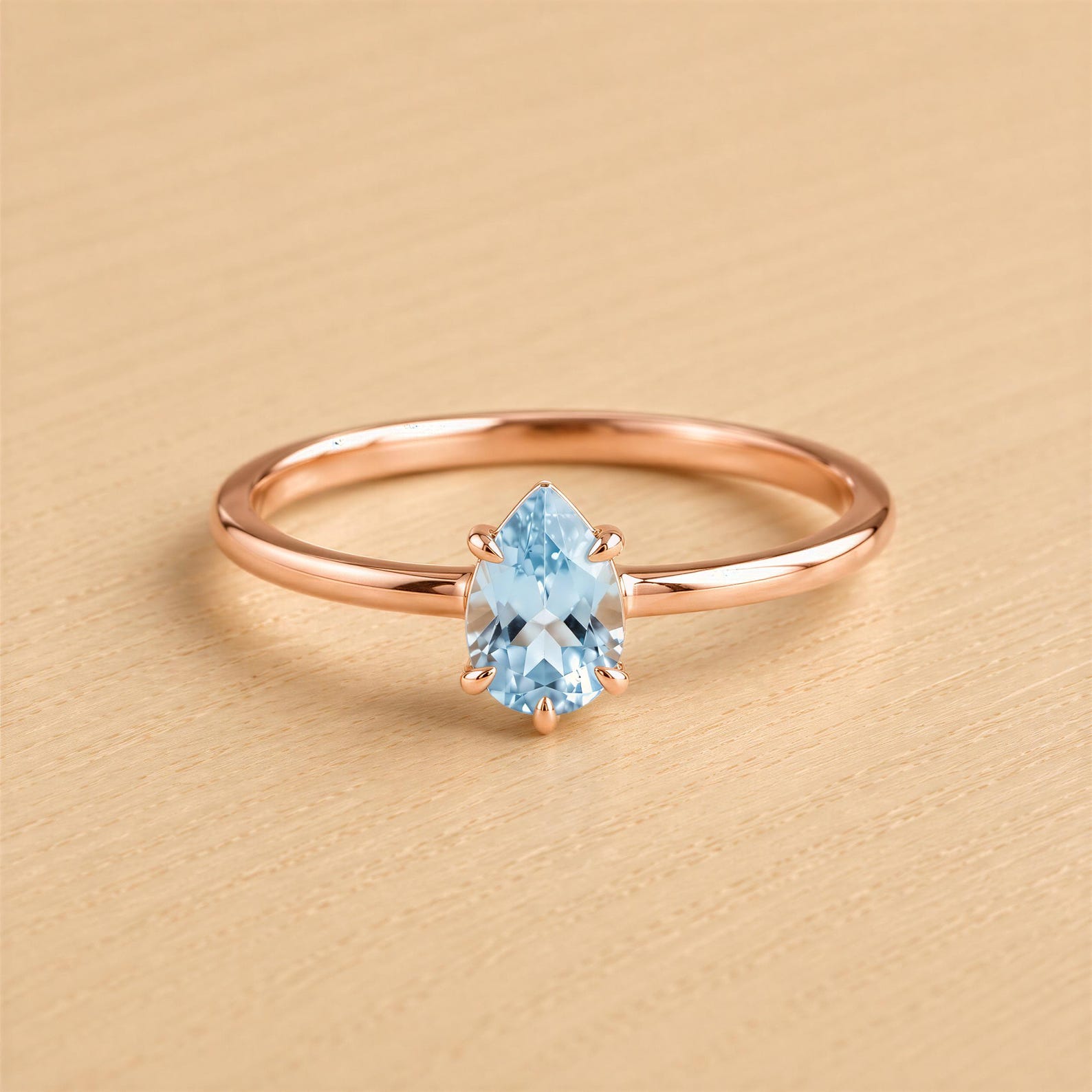A rose gold ring with a blue aquamarine gemstone set in the center.