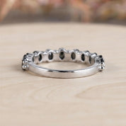 A silver ring with a row of small diamonds or stones set in the band, resting on a wooden surface.