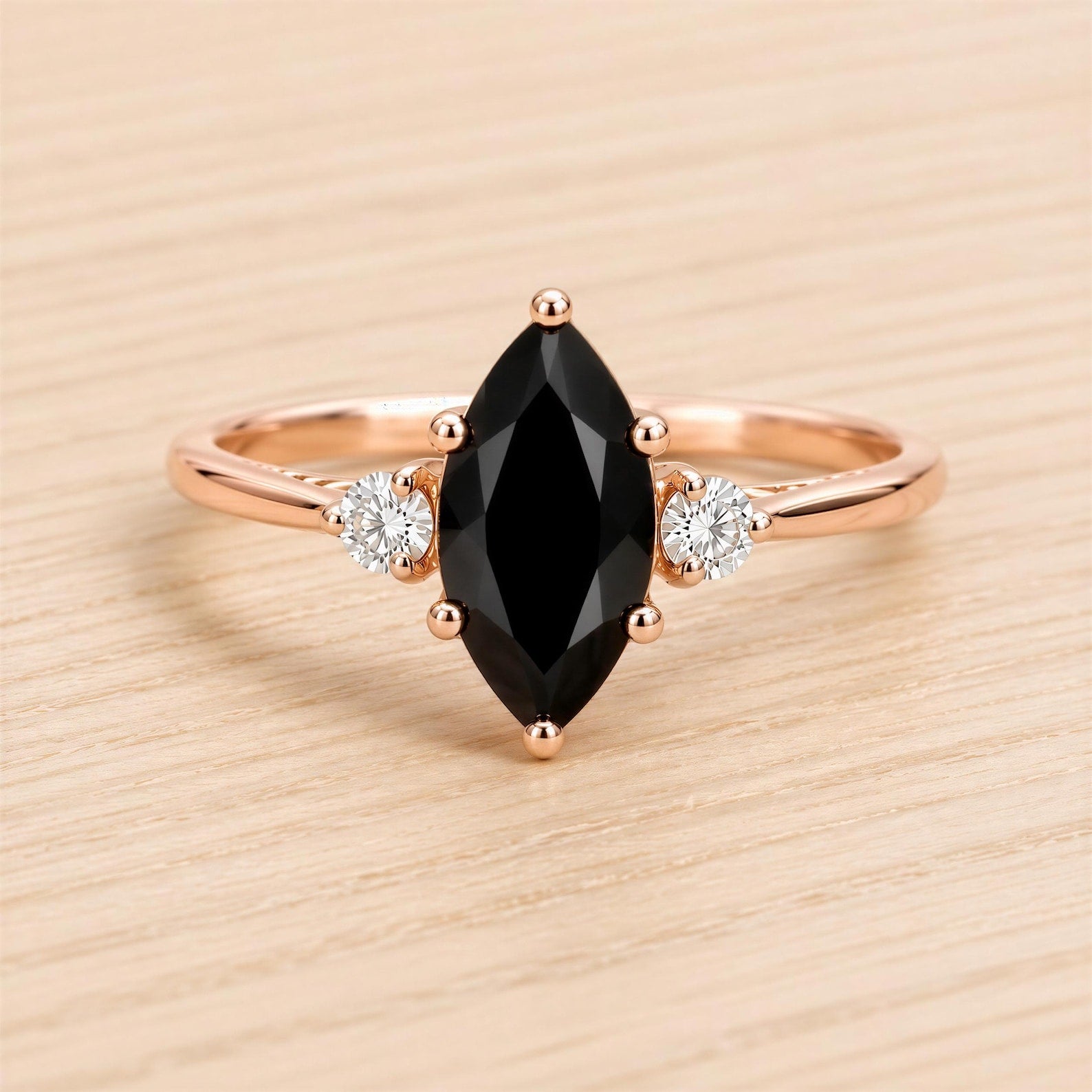 A rose gold ring with a large black gemstone and two smaller diamonds set in the center.