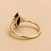 A gold ring with a large black gemstone, possibly a diamond, set in the center.
