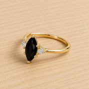 A gold ring with a large black gemstone, possibly a diamond, set in the center.
