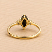 A gold ring with a large black gemstone, possibly a diamond, set in the center.