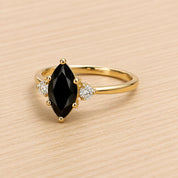 A gold ring with a large black gemstone, possibly a diamond, set in the center.