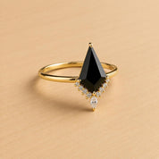 A gold ring with a large black gemstone, possibly a diamond, set in the center.