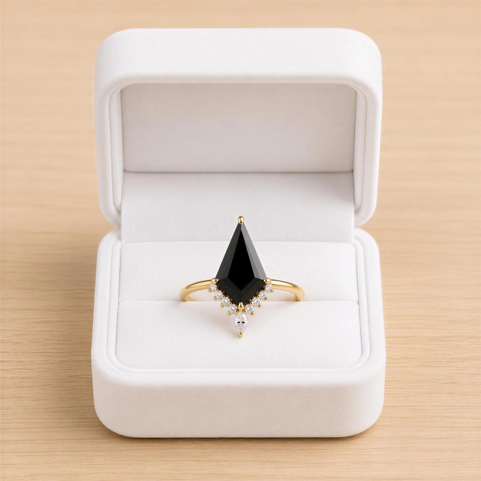 A white jewelry box containing a gold ring with a large black gemstone and smaller diamonds.