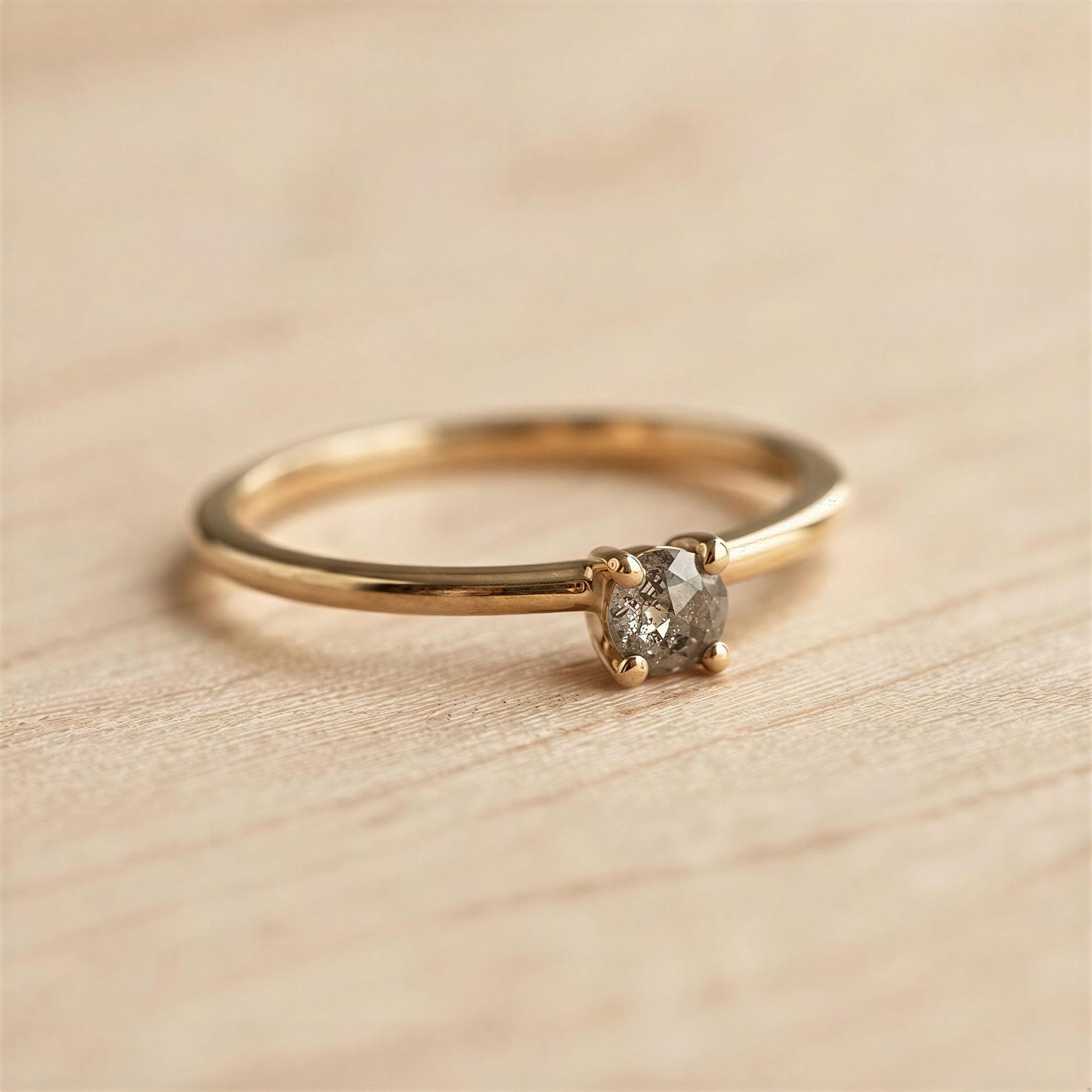 A gold ring with a diamond set in the center, resting on a wooden surface.