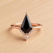 A ring with a large black diamond as the centerpiece, surrounded by smaller diamonds and a rose gold band.